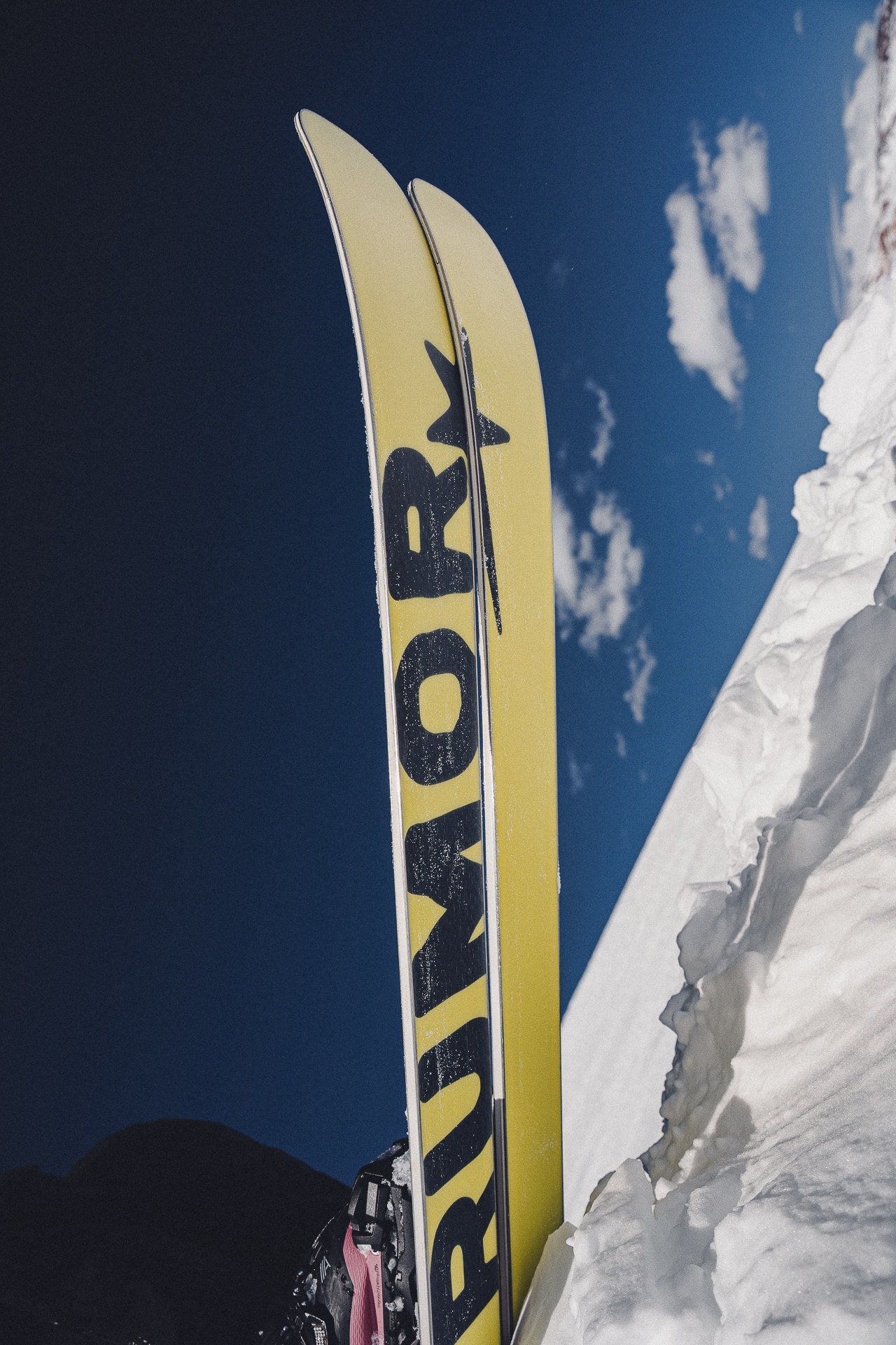 A pair of HEARSAY skis against a deep blue sky, the wordmark showing